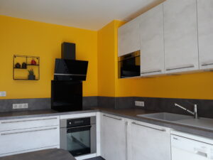 Cuisine moderne gris clair avec mur jaune moutarde et électroménager intégré, installation réalisée par HomeSweety