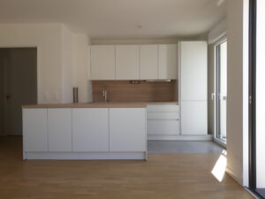 Cuisine moderne blanche avec îlot central et plan de travail effet bois, installation réalisée par HomeSweety