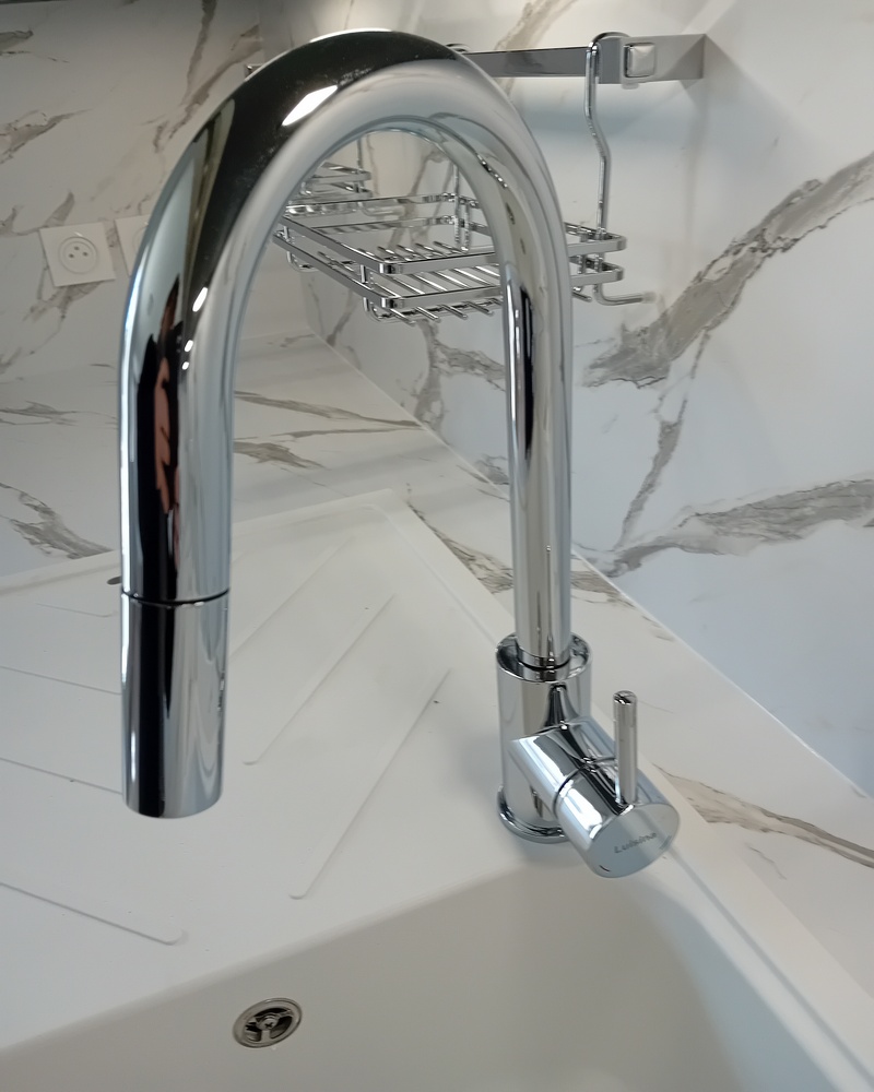 plombier professionnel réparant fuite d'eau sous évier cuisine Essonne