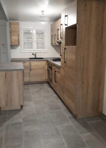 Cuisine moderne en bois avec plan de travail gris et poignées noires, installation réalisée par Homesweety.